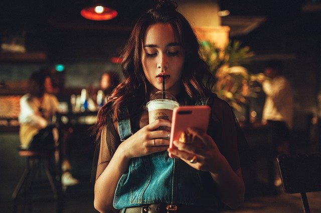 žena s drinkem a mobilem